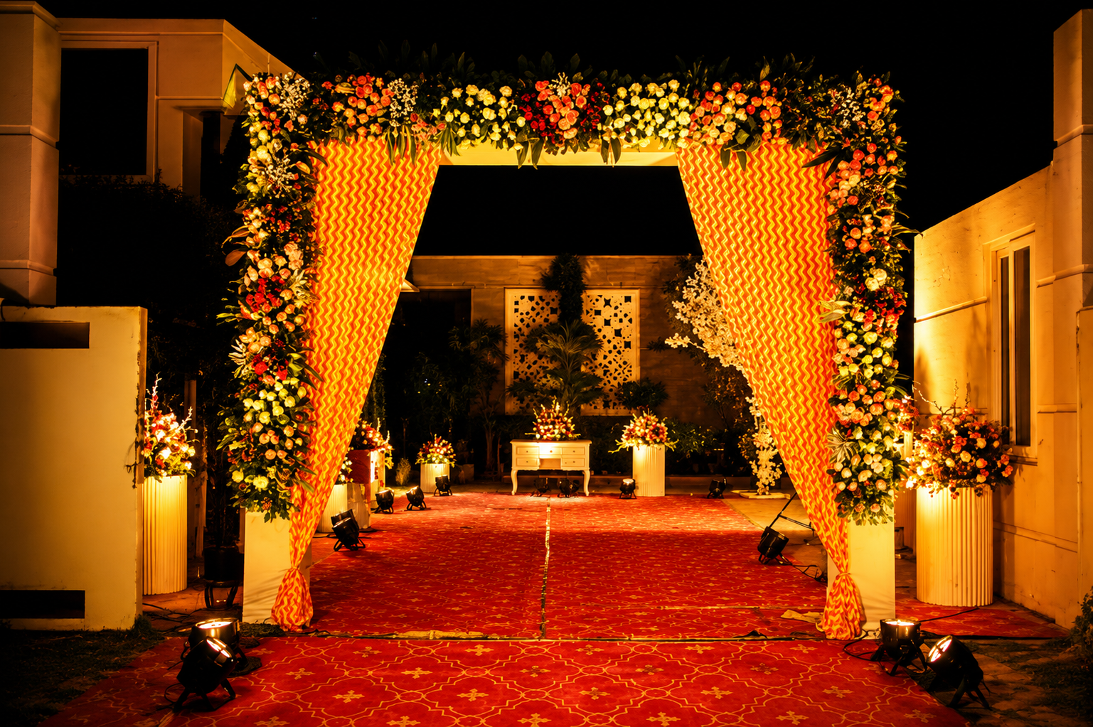 Floral entrance arch with warm lighting and red carpet
