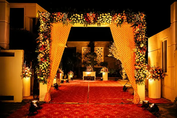 Floral entrance arch with warm lighting and red carpet