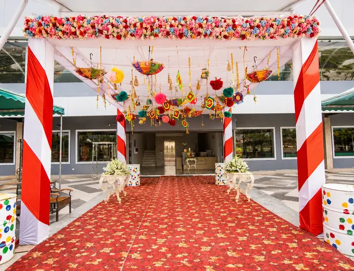 Floral welcome entrance with red carpet and hanging umbrellas